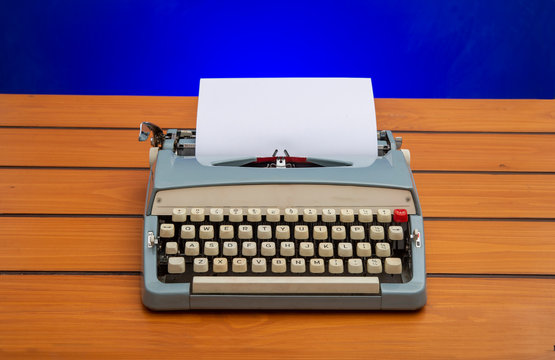 Old manual typewriter with white paper on wooden table, copy space banner