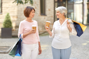 Wall Mural - sale, consumerism and people concept - two senior women or friends with shopping bags drinking takeaway coffee on tallinn city street