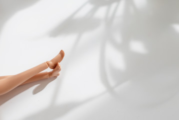 doll legs on background with plant shadows. creative minimalistic concept of relax. 