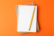 © New Africa - Notebooks with pencil on orange background, top view