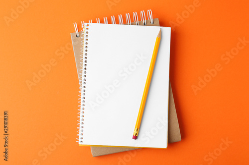 Cuadros en Lienzo Notebooks with pencil on orange background, top view