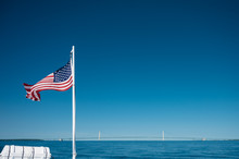American Flag Flying With A View Of Mackinac Bridge And Lake Huron