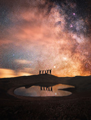 Wall Mural - silhouette of a group of people standing on a mountain. behind their beautiful starry sky and the mi