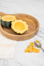 Fresh Acorn Squash Cut In Half With Seeds Scooped Out Of One Half; Seeds And Spoon On Countertop
