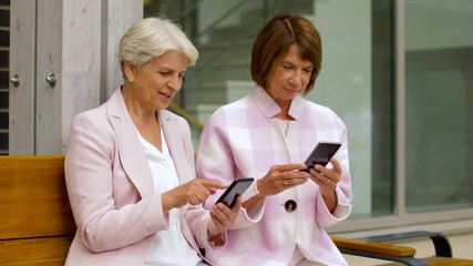 Wall Mural - technology, old age and people concept - happy senior women or friends with smartphones in city