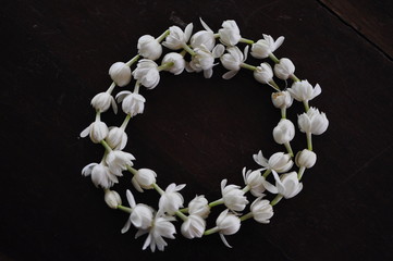 Fragrant jasmine blossom garland wrapped in circle on wooden table traditionally used as an offering to the ghosts and spirits in Thailand.