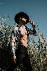 Wall Mural - Portrait of a handsome young man in a black hat. Fashion country concept. Outdoor shot.