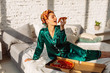 © Sergey Chumakov - young cheerful woman in silk nightwear eating tasty pizza in bed, unhealthy eating