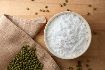 Wall Mural - Top view mung bean starch powder in white bowl with wooden background