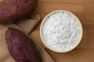 Wall Mural - Top view of sweet potato starch in white bowl with sweet potato wooden table background