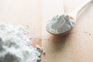 Wall Mural - Close-up of tapioca starch or flour powder in wooden spoon with wooden background