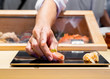 Japanese Sushi Chef serve sushi by hand on the black shimmer plate. (Omakase sushi course) Selective focus on sushi.
