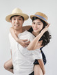 © nuiiko - Happy Asian couple wearing hat and ride piggyback on white background.