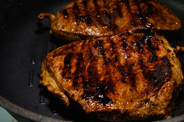 Wall Mural - Two pieces of beef fried in a black skillet grill. Grill meat pan. Cooking a beef steak. 