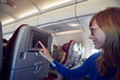 © astrosystem - Woman using touchscreen in modern airplane seat.