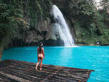 Fit Woman Alone On The Bamboo Raft In Front Of The Waterfall With Turquoise Water In Kawasan Falls In Cebu Island, Philippines