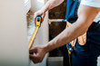 cropped view of handyman measuring wall with yellow measuring tape