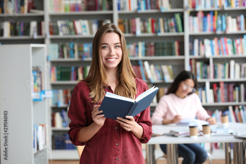 Cuadros en Lienzo Young pretty woman with book in library