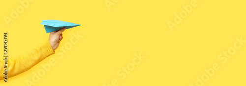 Fotografía hand holding paper plane over yellow background, panoramic mock up image