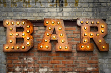 Inscription From Large Metal Letters Decorated With Glowing Light Bulbs On The Brick Wall