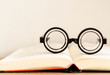 soft focus glasses with blur books stack on wooden desk in university or public library room or book store.concept of knowledge and education.