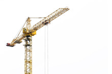Yellow Construction Crane On A White Isolated Background Builds Multi-storey Residential Buildings Using Modern Technologies Of Metal, Concrete And Brick According To The Architectural Design