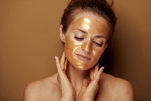 Relaxed Woman With Golden Mask Against Beige Background