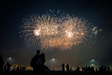 Silhouettes Of People Watching Fireworks In The Background Of Bright Flashes In The Night Sky