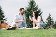 © LIGHTFIELD STUDIOS - handsome man with disabled girlfriend holding glasses of white wine while sitting on blanket in park
