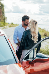 Wall Mural - blonde woman and handsome man kissing and hugging near car