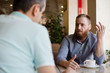 © ruslanshug - two men discussing difficult issues with emotions during coffee break in cafe talking about problems of business negotiation