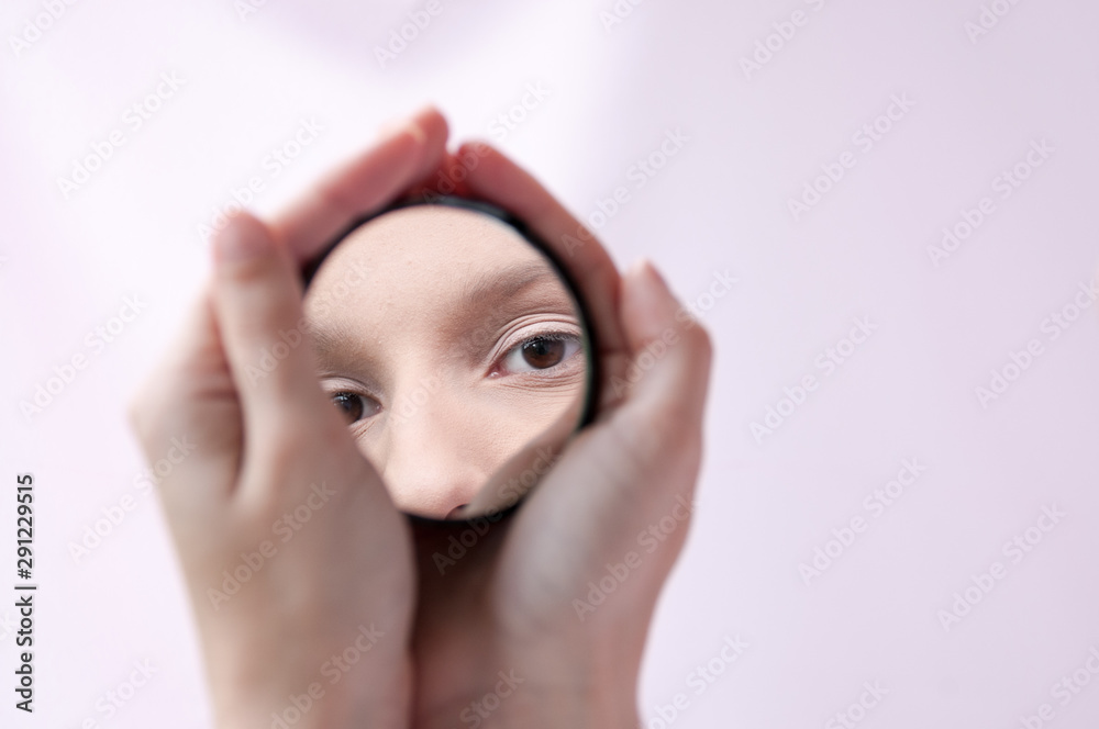 Hands holding a mirror with a reflection of the girl's eyes - obrazy, fototapety, plakaty 