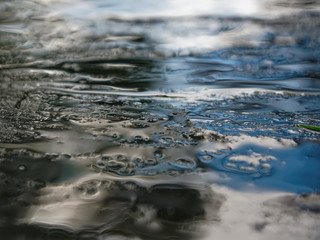 Drops of water on a black and blue stone background. Wet stone background after rain. Reflection of the sky in drops.