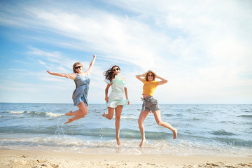 Poster - Happy jumping young women on sea beach at resort