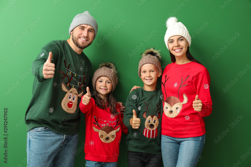 Happy family in Christmas sweaters on color background