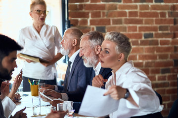 Wall Mural - Group of five caucasian businessmen wear stylish office clothes at table in office discuss project