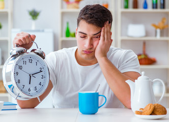 Canvas Print - Man with alarm clock falling asleep at breakfast