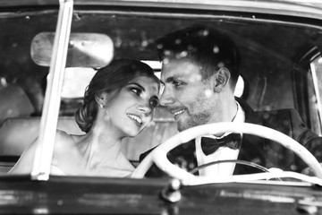 photo in retro style. happy bride and groom sitting in the car