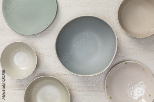 Fotomural Group of empty blank ceramic round bowls and plates on white stone blackground,