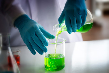 Wall Mural - laboratory research concept; scientist pour chemical reagent from flask to beaker. research in chemi
