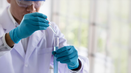Wall Mural - laboratory research concept; scientist dropping chemical reagent into test tube. research in chemica