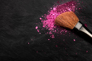 Wall Mural - Make-up brush with crushed cosmetics, shot from above on a black background with a place for text, a beauty design template for a makeup banner