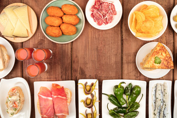 Wall Mural - Spanish tapas, a variety of snacks, top shot. Gazpacho, tortilla, jamon, cheese etc, shot from the top on a dark rustic wooden background with a place for text