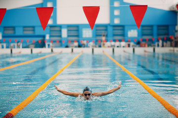 Young woman swimmer swims in swimming pool