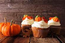 Fall Pumpkin Spice Cupcakes With Creamy Frosting And Autumn Toppings. Scene Against A Rustic Wood Background.