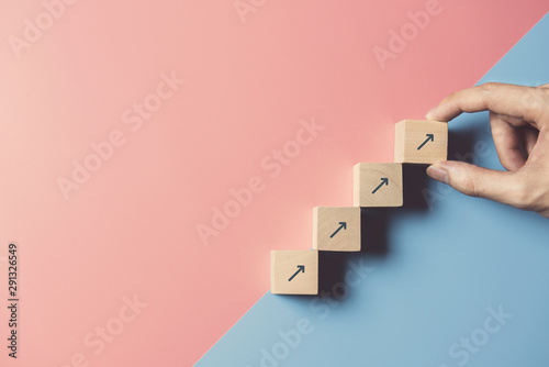 Fotomural Business concept growth success process, Close up man hand arranging wood block stacking as step stair on paper blue and pink background, copy space