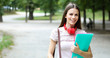 © Minerva Studio - Female student holding walking outdoor in the park and smiling