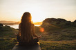 Leinwandbild Motiv Woman meditating yoga alone at sunrise mountains. View from behind. Travel Lifestyle spiritual relaxation concept. Harmony with nature.
