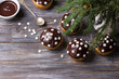 Spicy pumpkin muffins with nuts, decorated with chocolate glaze and sugar snowflakes under the Christmas tree on a wooden table, free space, selective focus, horizontal. tasty homemade holiday food	