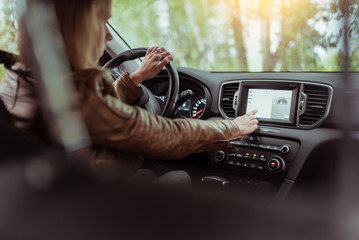 Woman girl in summer car interior in forest park, selects navigation touch screen, satellite internet application. Lost in search of a route, parking in the fresh air rest in the forest.